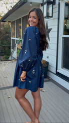 Navy long sleeve babydoll mini dress with floral embroidery detail and relaxed silhouette.