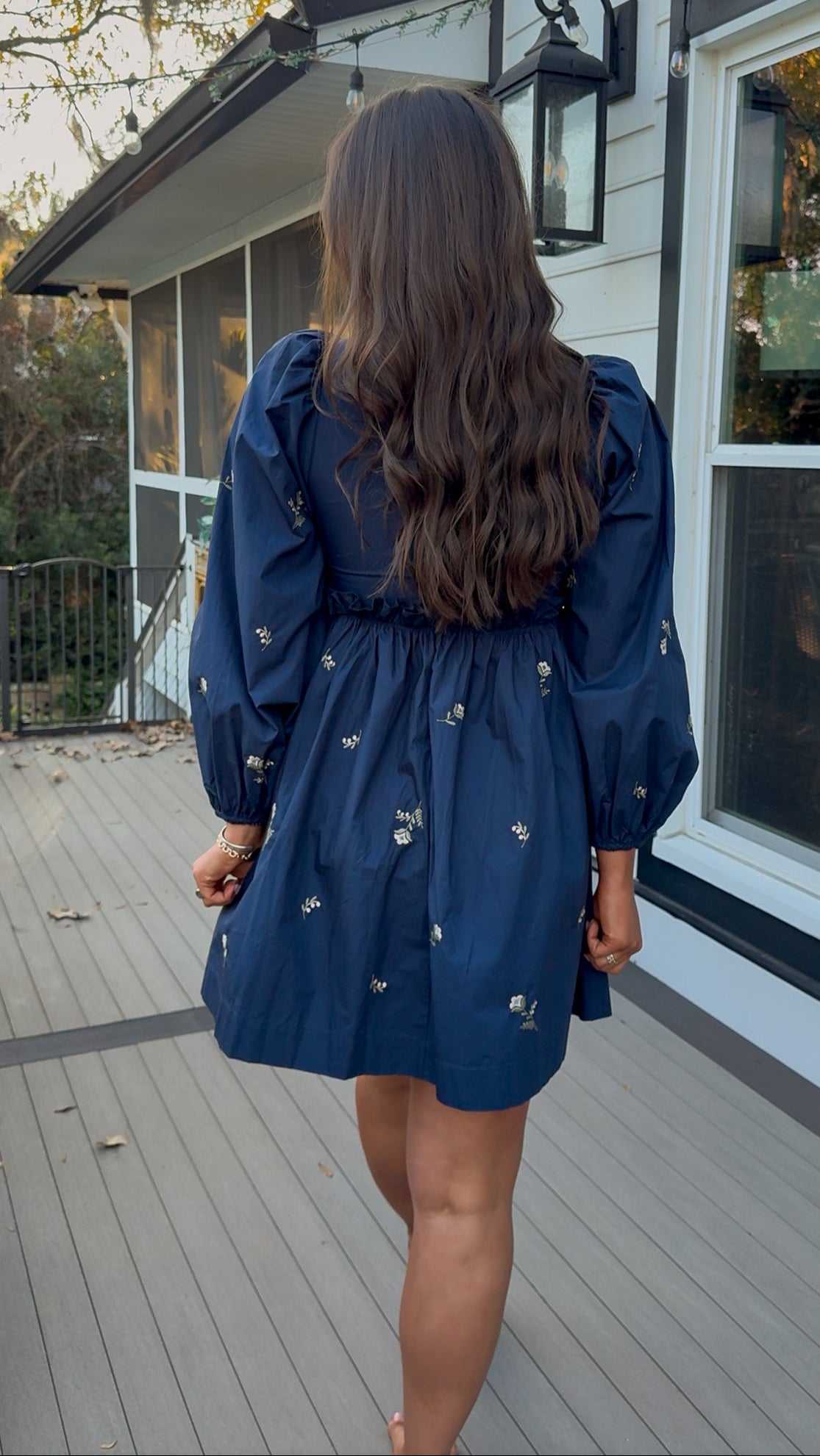 Navy long sleeve babydoll mini dress with floral embroidery detail and relaxed silhouette.