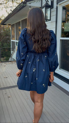 Navy long sleeve babydoll mini dress with floral embroidery detail and relaxed silhouette.