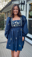 Navy long sleeve babydoll mini dress with floral embroidery detail and relaxed silhouette.