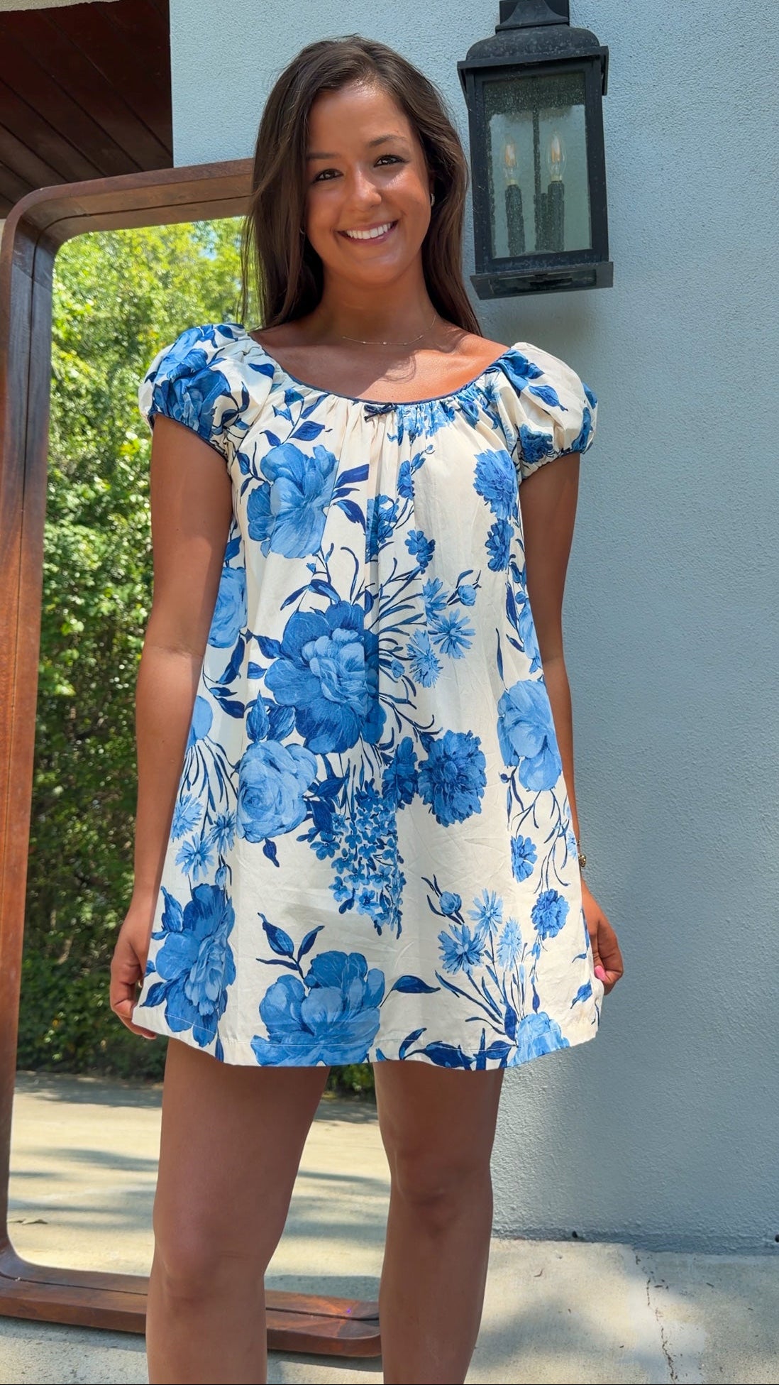 Woman wearing a blue floral dress standing outdoors.