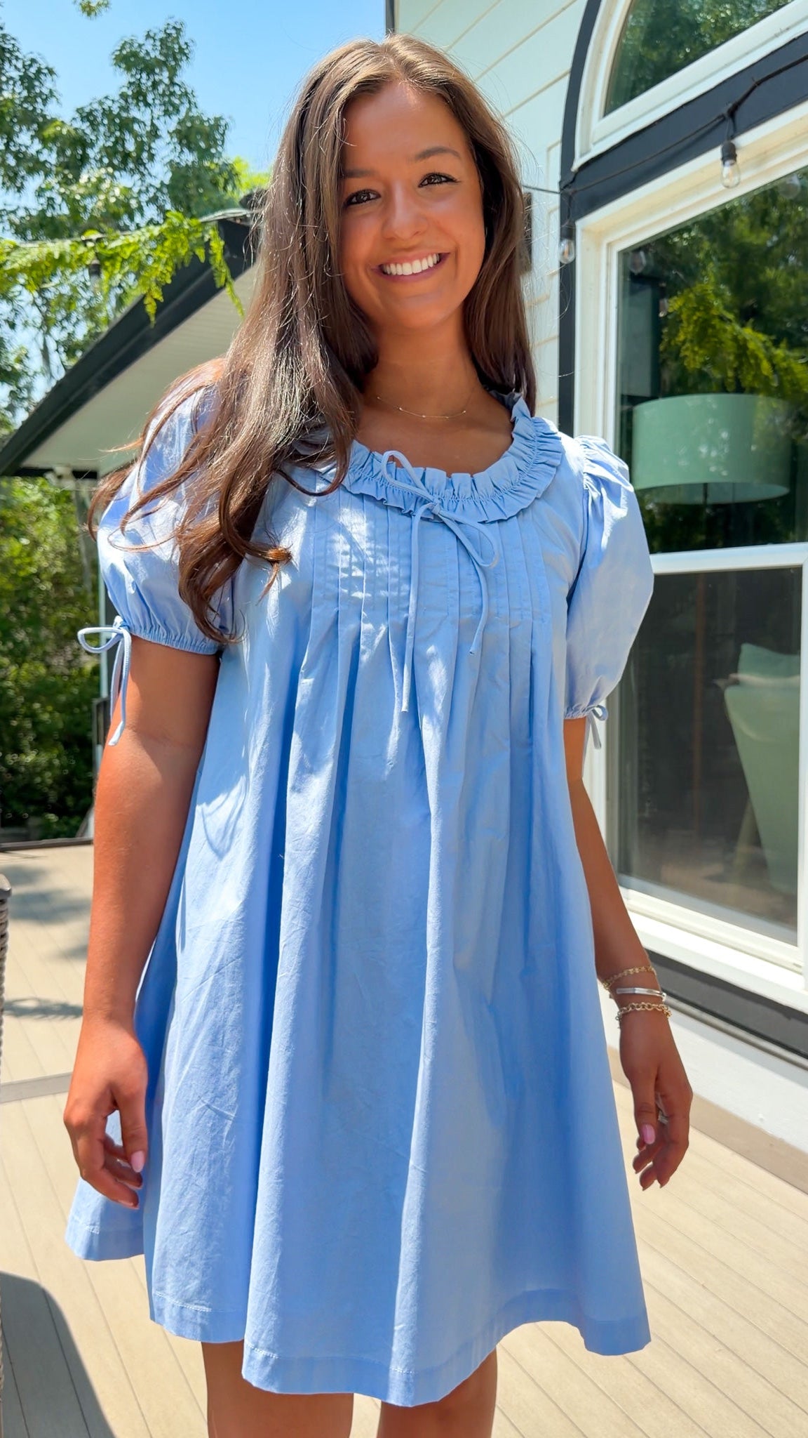Woman wearing a light blue dress standing outdoors.