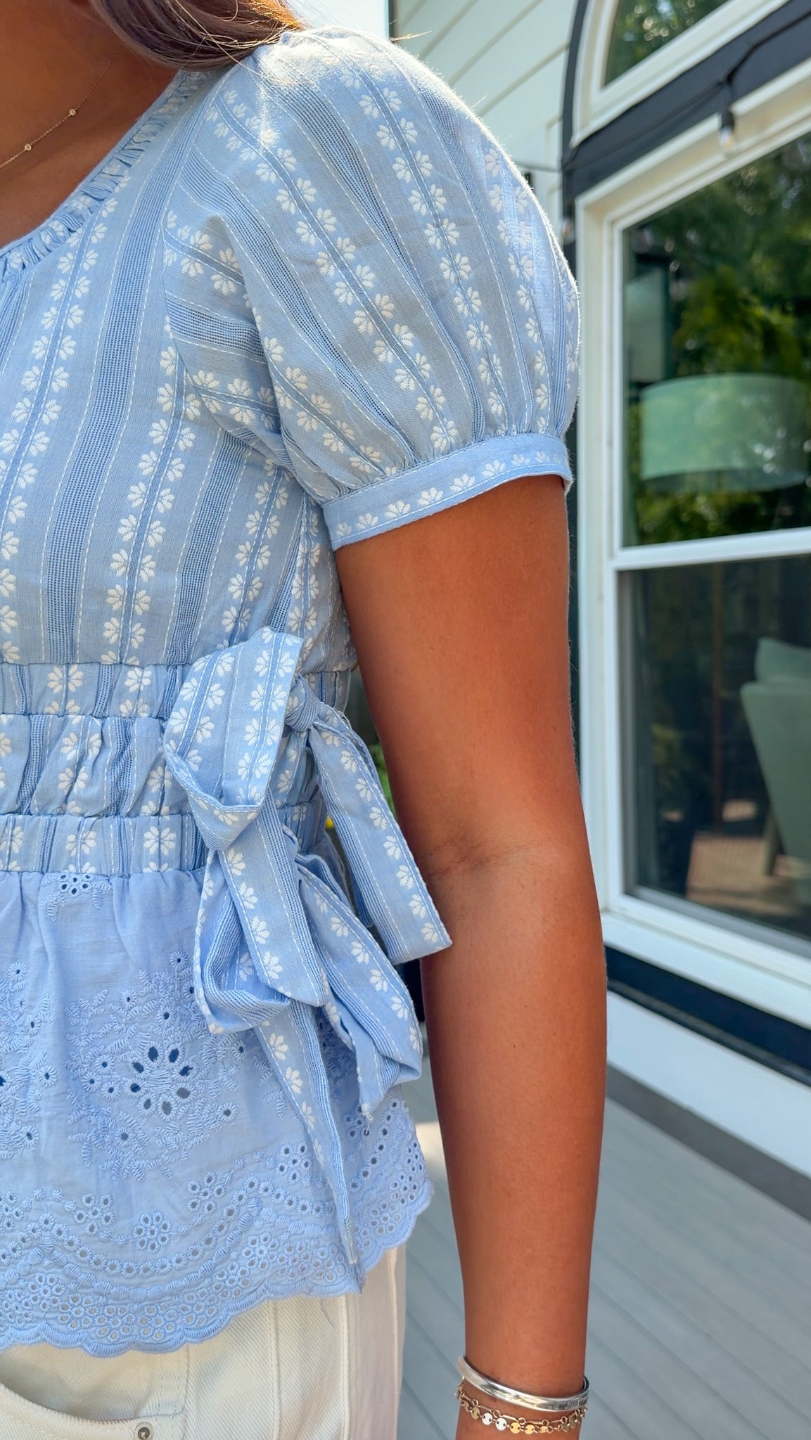 Light blue dress with floral patterns worn by a person, standing in front of a window.