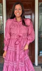 a satin midi dress with crochet lace panels, button-down front, long sleeves, and a self-tie waist in a soft plum color. pink mauve high neck 