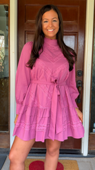 Woman wearing a pink dress standing in front of a door.