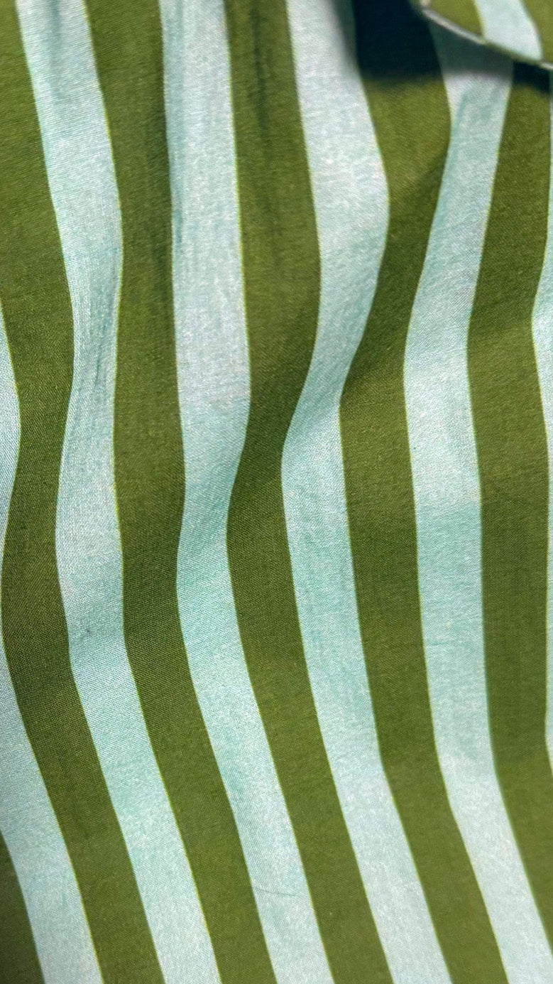 A close-up of a striped fabric with alternating vertical stripes of olive green and white, showing a soft texture and a small portion of a matching fabric tab at the top right.