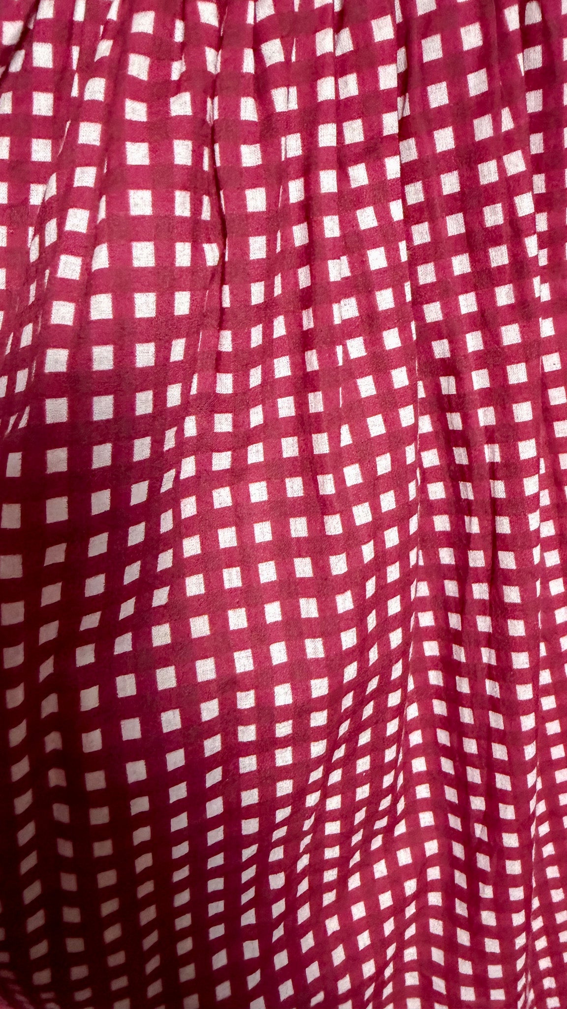 A close-up of a red and white gingham patterned fabric, showing the texture and a subtle sheen.