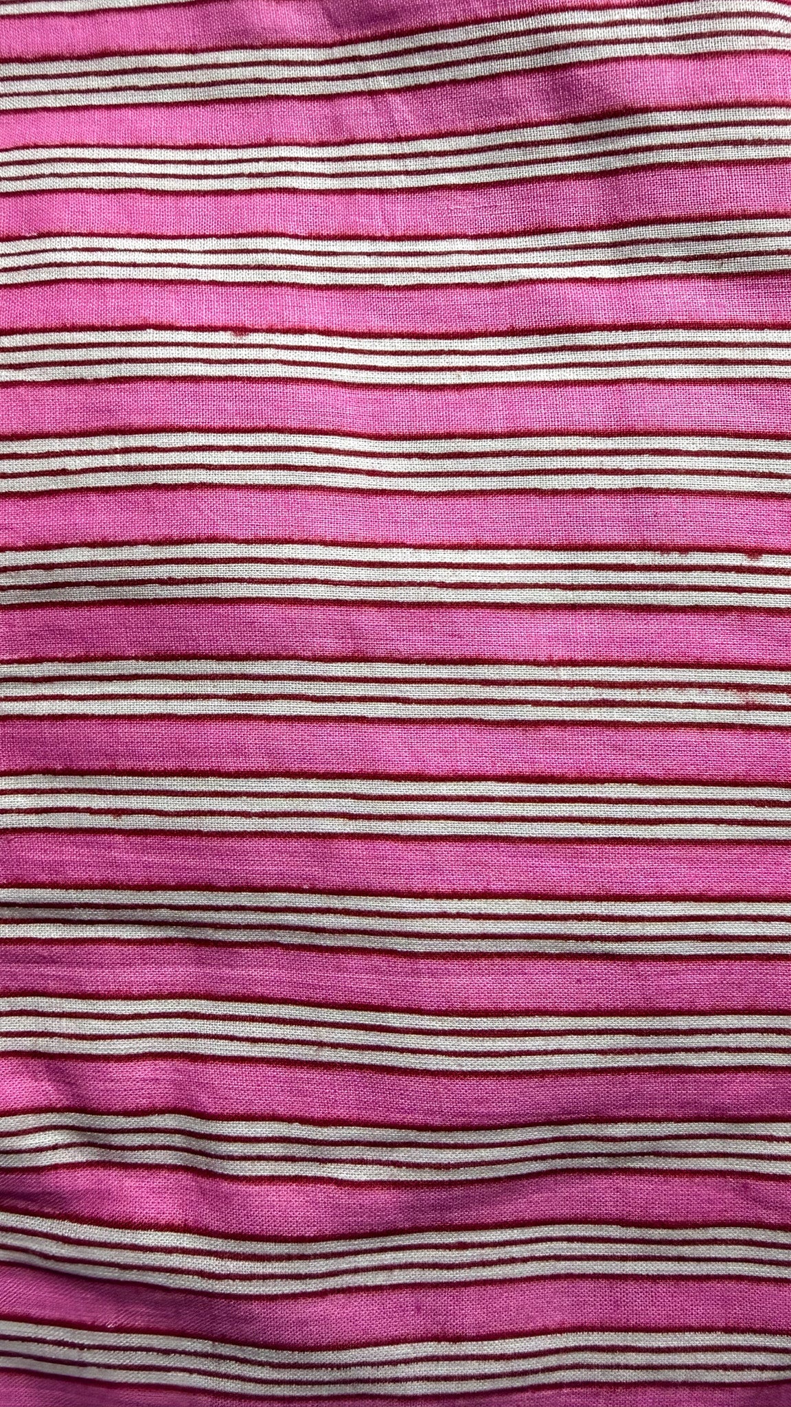 A close-up of a pink striped fabric with horizontal stripes in cream and dark brown.