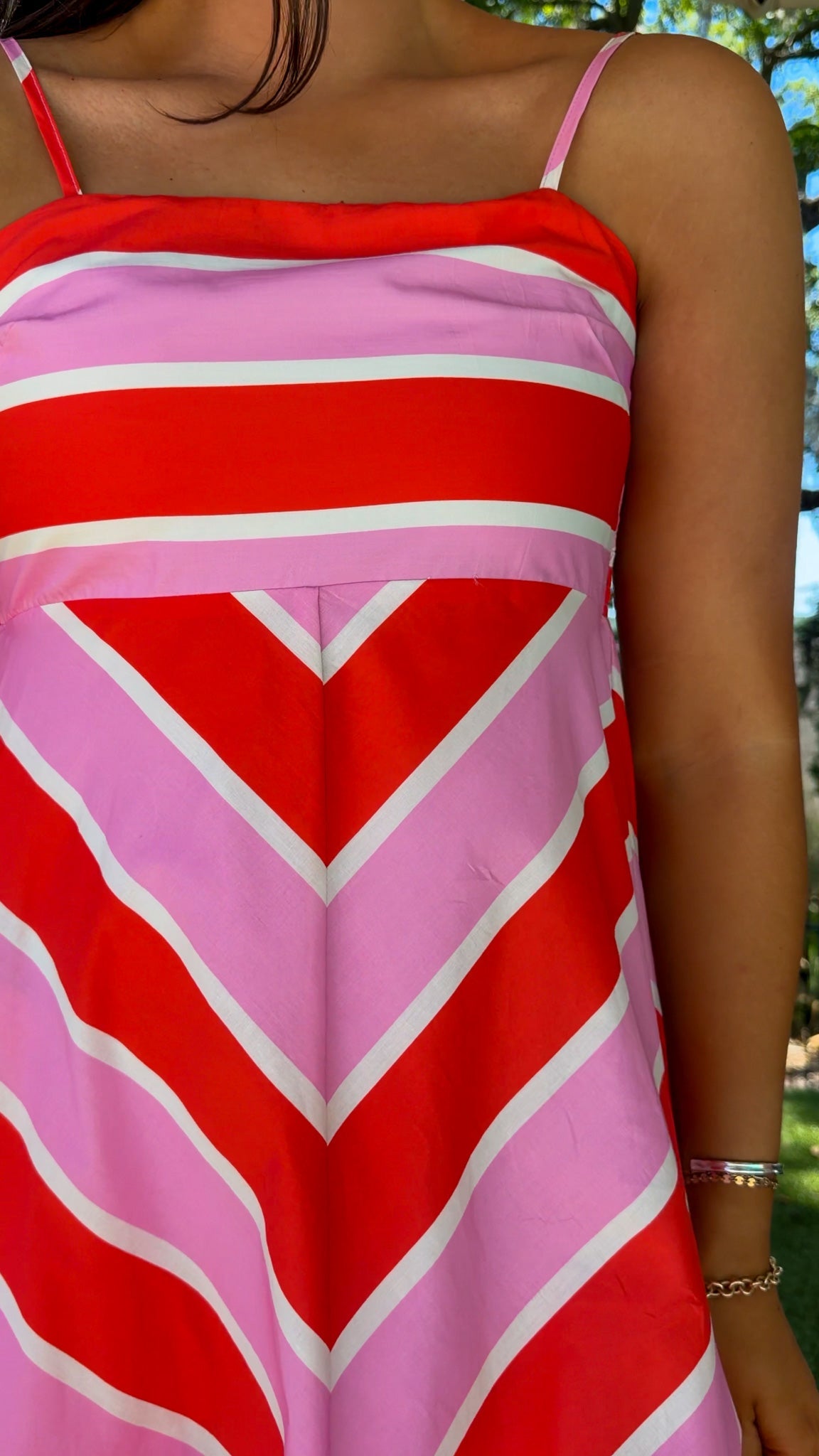 Person wearing a red and pink striped dress with a blurred background