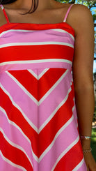Person wearing a red and pink striped dress with a blurred background
