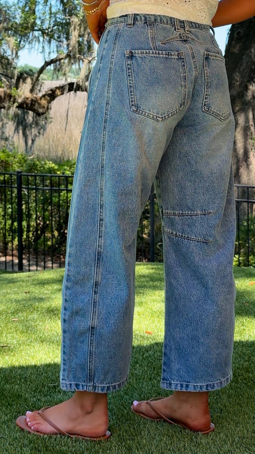 Person wearing blue jeans standing on grass with trees in the background