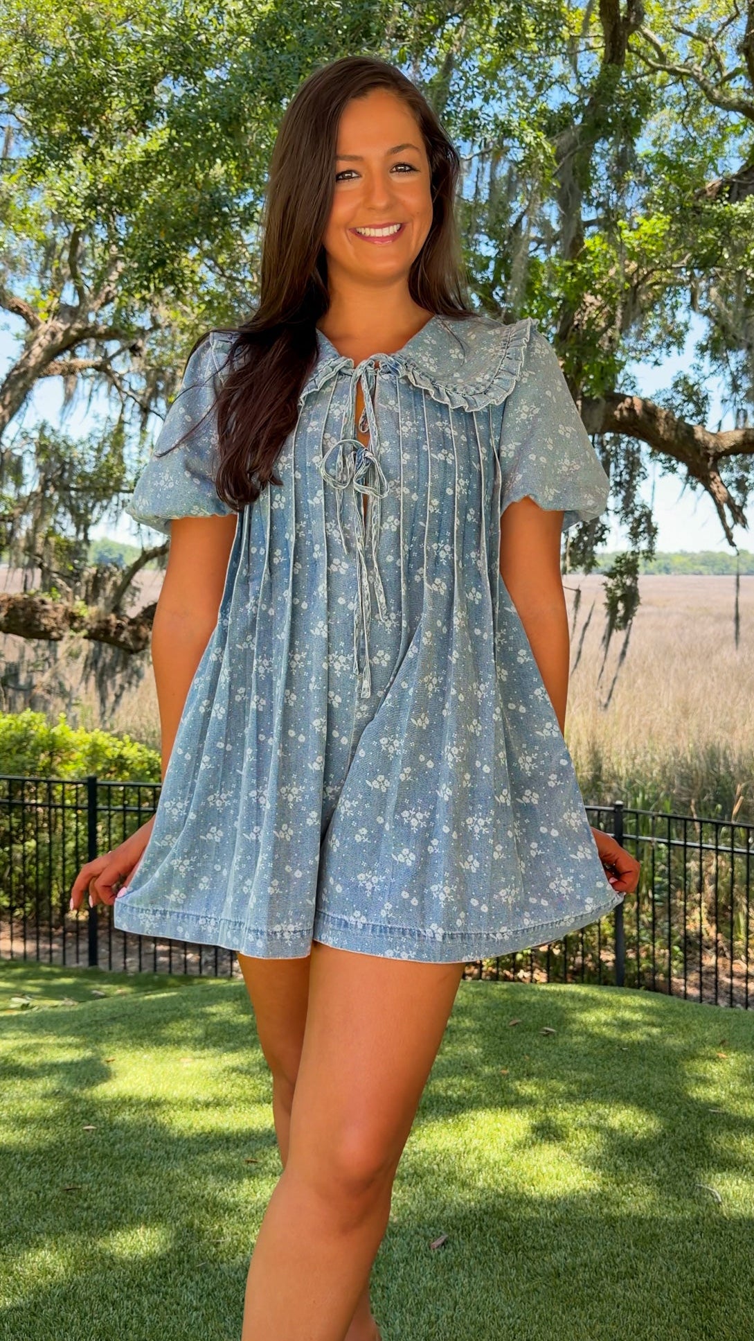 Woman wearing a blue dress with a floral pattern in an outdoor setting