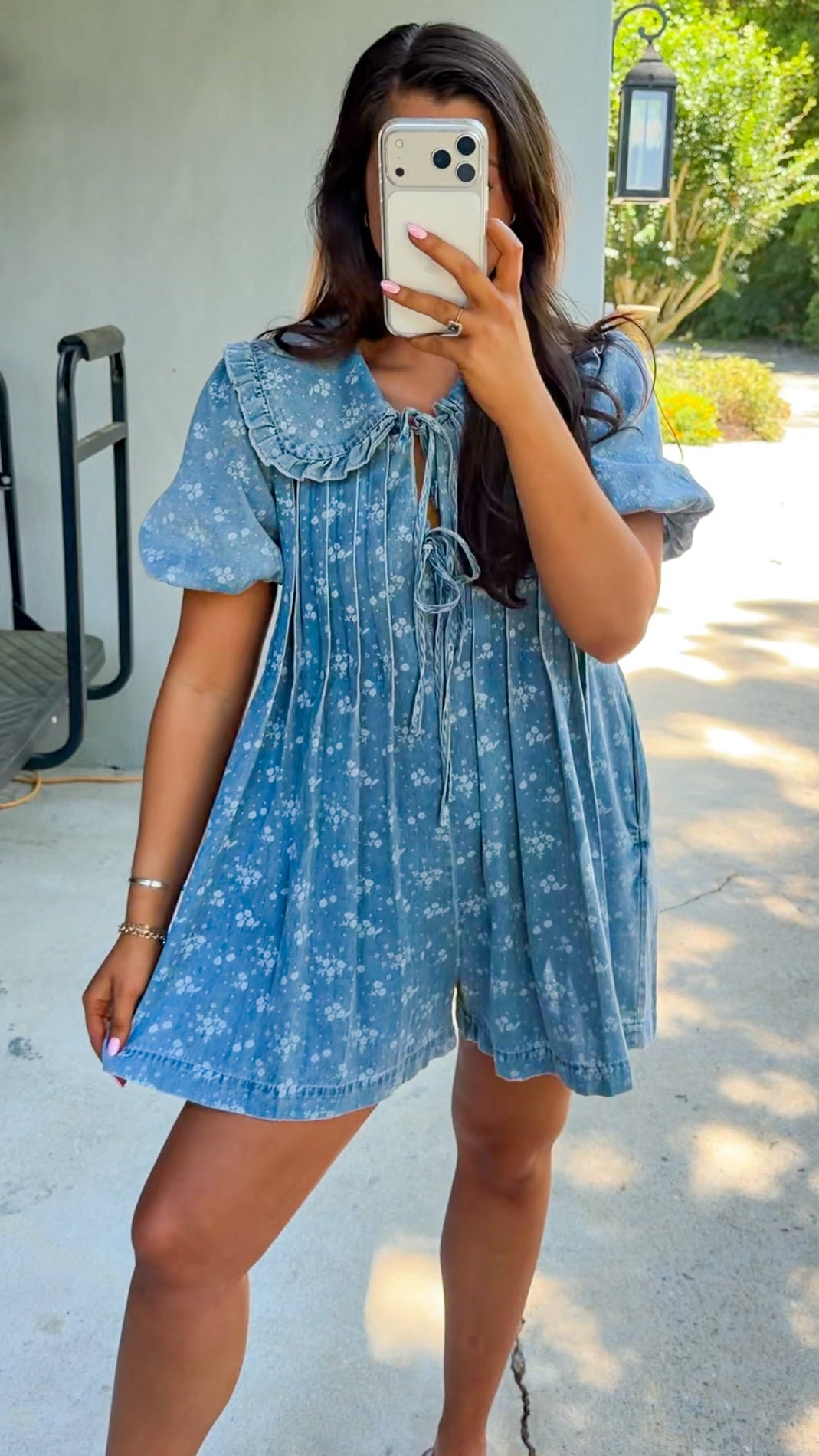 Woman taking a mirror selfie wearing a blue dress with white floral pattern.