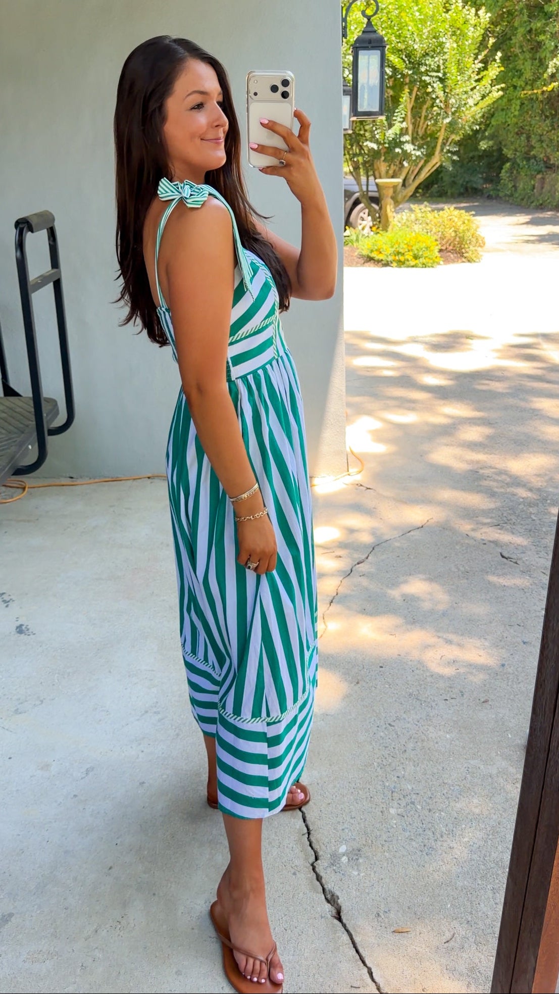 Woman taking a selfie wearing a green and white striped dress outdoors.