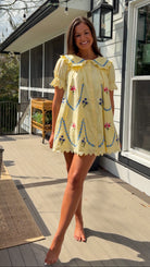 yellow mini dress with multicolor floral embroidery, ruffle collar, puff sleeves, and scalloped hem