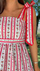 Woman wearing a red and white patterned dress with floral details outdoors.