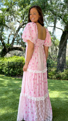 Pink floral maxi dress with delicate rose print, lace-trimmed V-neckline, puff short sleeves, empire waist, smocked back, and tiered skirt with lace panel details