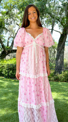 Pink floral maxi dress with delicate rose print, lace-trimmed V-neckline, puff short sleeves, empire waist, smocked back, and tiered skirt with lace panel details
