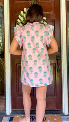 Pink and green floral mini dress with flutter sleeves, a ruffled stand neckline, decorative frog button closures, and a relaxed shift silhouette.