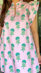 Pink and green floral mini dress with flutter sleeves, a ruffled stand neckline, decorative frog button closures, and a relaxed shift silhouette.