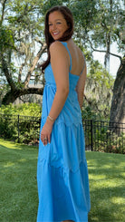 Blue midi dress featuring a square neckline, adjustable scalloped shoulder straps, scalloped trim at the empire waist and tiered skirt, a smocked back, and a flowing A-line silhouette.