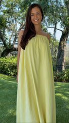 Butter yellow pinstripe maxi dress featuring adjustable spaghetti straps, a gathered square neckline, and a relaxed flowy silhouette in a lightweight woven fabric.