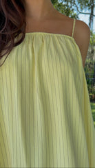 Butter yellow pinstripe maxi dress featuring adjustable spaghetti straps, a gathered square neckline, and a relaxed flowy silhouette in a lightweight woven fabric.