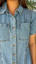 Light wash chambray midi dress featuring a collared neckline, functional button-front closure, oversized chest pockets, short sleeves, side pockets, and a relaxed silhouette.