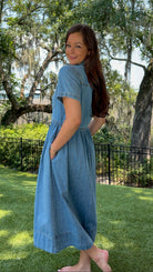 Light wash chambray midi dress featuring a collared neckline, functional button-front closure, oversized chest pockets, short sleeves, side pockets, and a relaxed silhouette.
