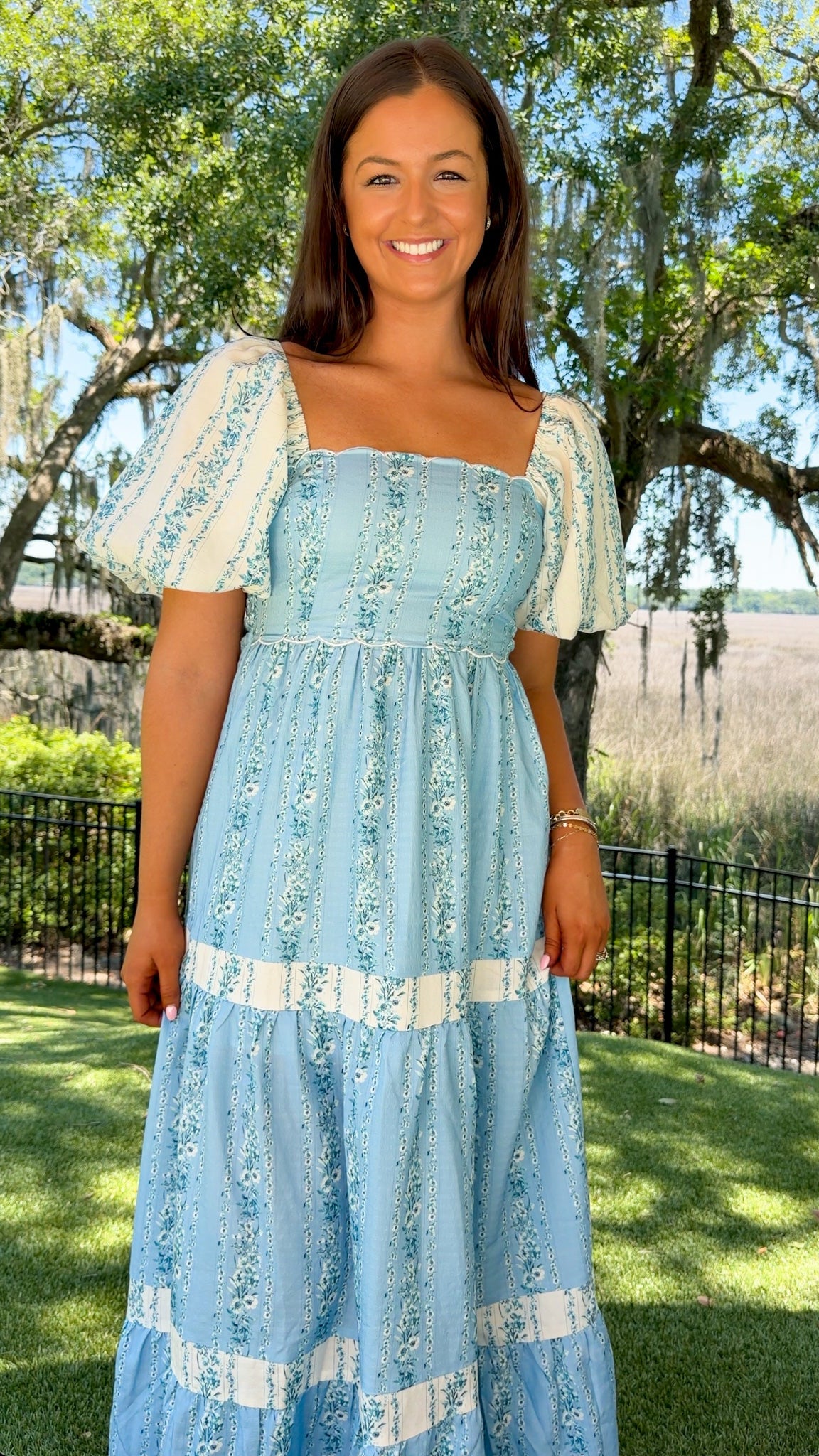 Woman wearing a light blue dress with white patterns outdoors.