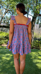 Woman wearing a blue plaid dress with red trim in a park setting