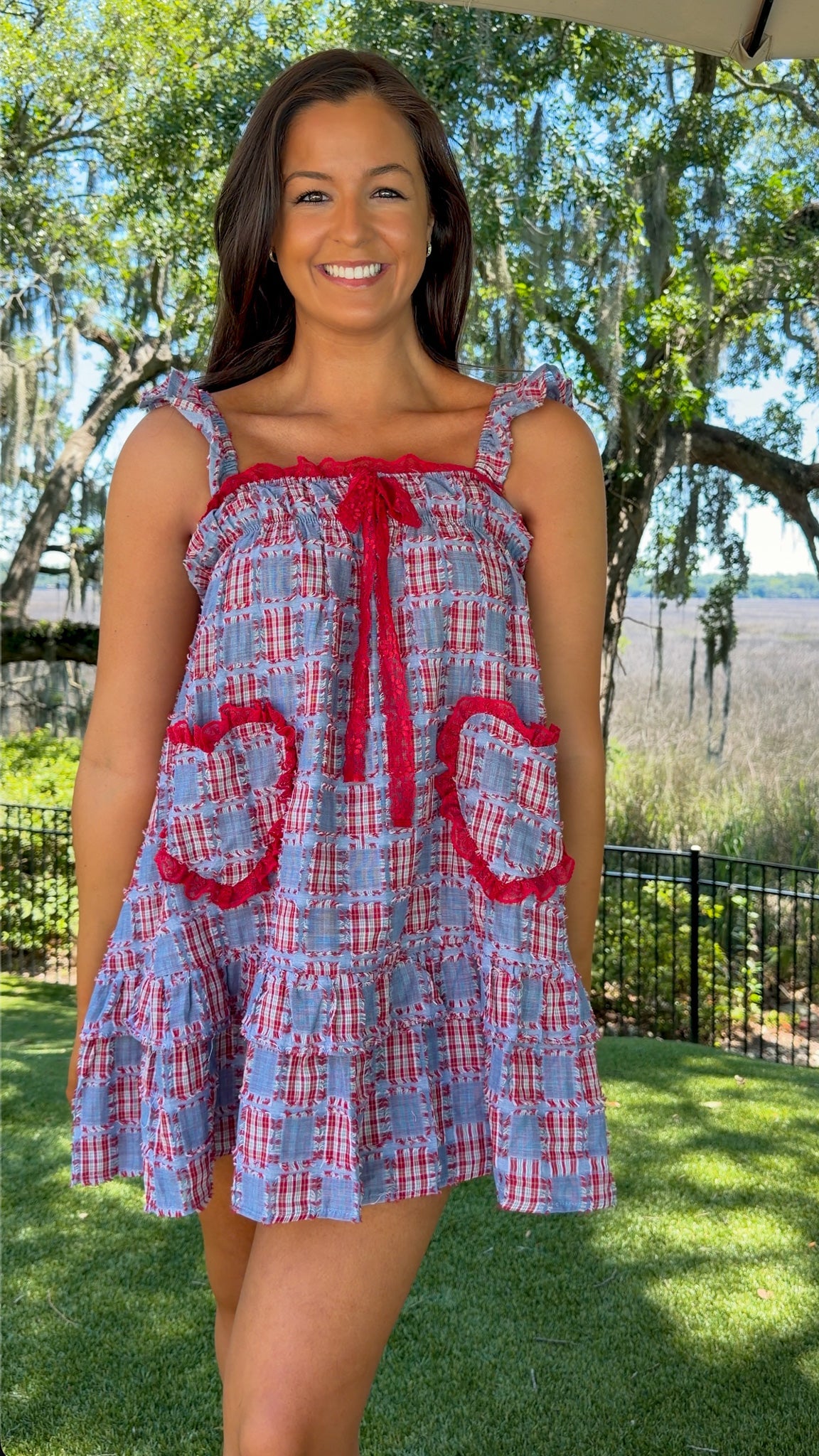 Woman wearing a blue and red checkered dress with floral details outdoors.