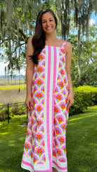 Woman in a floral dress standing outdoors with trees and grass in the background