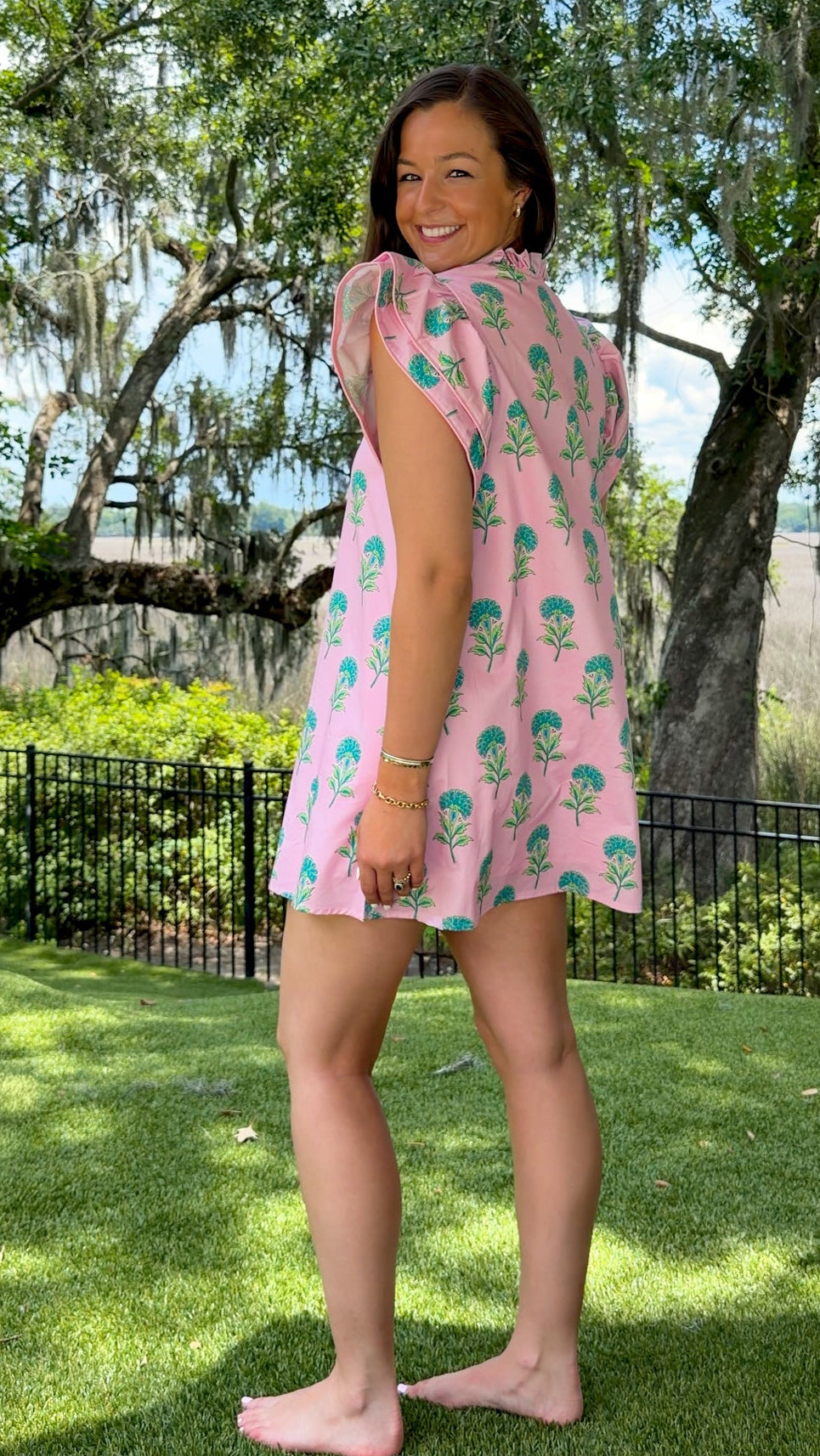 Pink and green floral mini dress with flutter sleeves, a ruffled stand neckline, decorative frog button closures, and a relaxed shift silhouette.