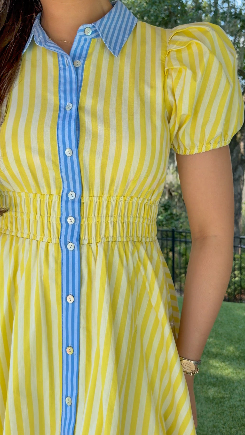 Yellow and ivory striped mini dress featuring a contrast blue collar and button placket, short puff sleeves, a smocked waist, side pockets, and a lightweight lined silhouette.