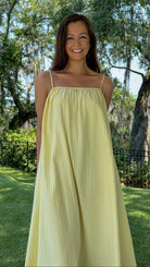 Butter yellow pinstripe maxi dress featuring adjustable spaghetti straps, a gathered square neckline, and a relaxed flowy silhouette in a lightweight woven fabric.