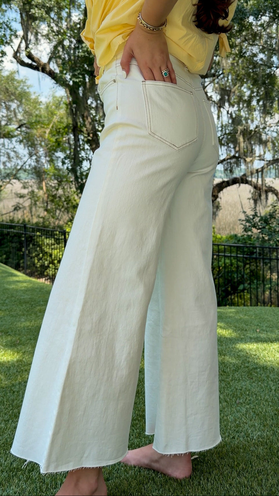 White high-rise wide leg denim jeans featuring contrast stitching, a cropped raw hem, front and back pockets, and a flattering structured fit.