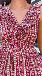 Close-up of a sleeveless ruffled dress with a deep V-neck, featuring a pink and olive green floral and striped pattern.